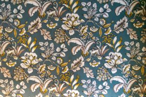 Blumentapete mit weißen, beigen und gelben Blumen und Blättern auf blaugrünem Hintergrund; dieses komplizierte Vintage-Muster verleiht einer Ferienwohnung mit Sauna Charme.