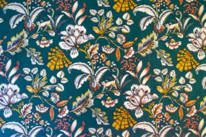 Blumentapete mit weißen und gelben Blumen, grünen Blättern und gelben Schmetterlingen auf einem blaugrünen Hintergrund - perfekt, um einer Ferienwohnung für zwei in der Oberlausitz einen lebendigen, dekorativen Touch zu verleihen.