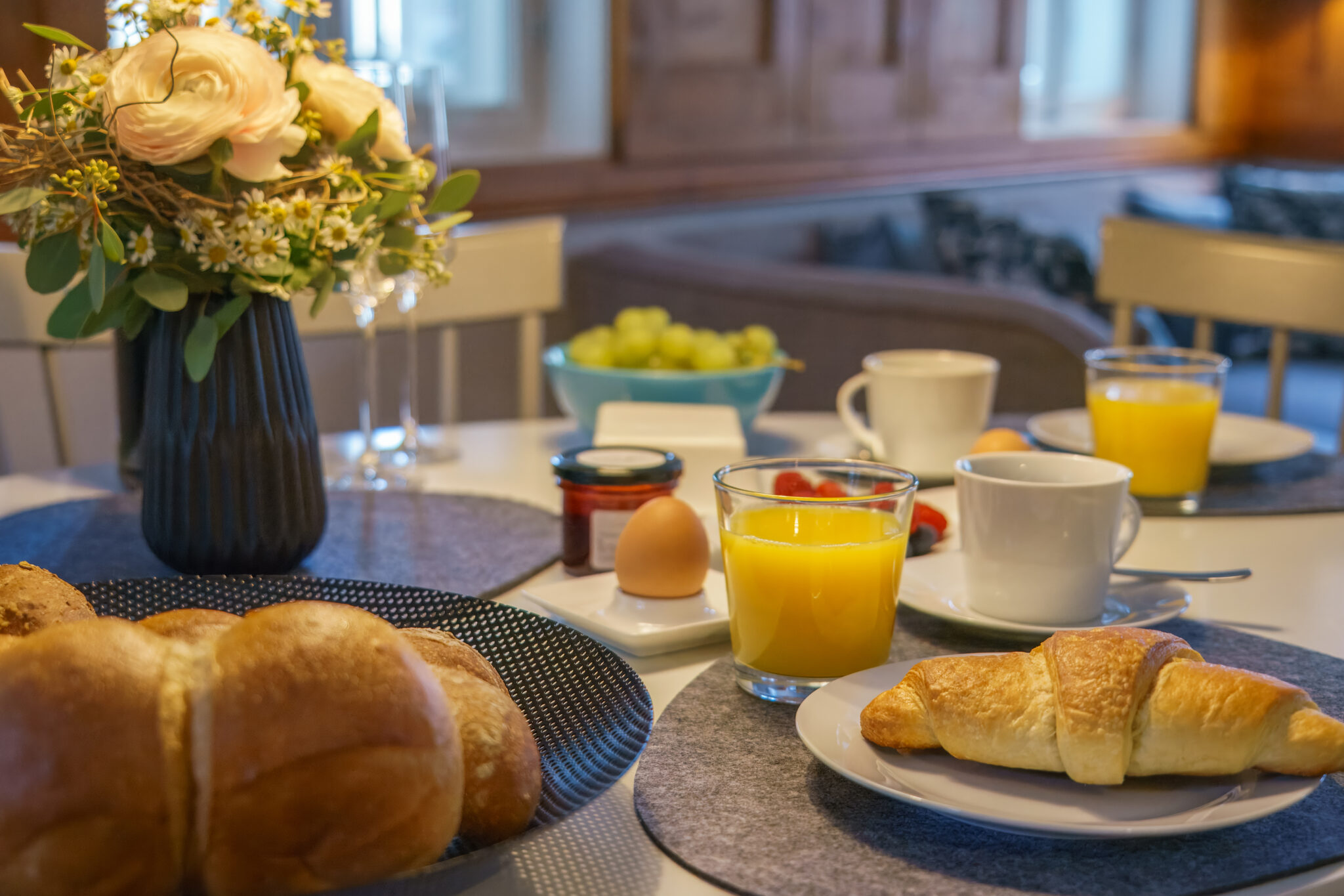 Ein gedeckter Frühstückstisch mit Orangensaft, Kaffee, einem Croissant und frischem Obst empfängt Sie in der gemütlichen Blockstube - Einfach mal raus - Wohlfühlzeit im Marktquartier 5.