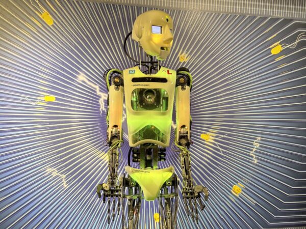 Ein humanoider Roboter mit durchsichtigem Brustkorb und neongrünen Teilen steht auf einem Podest, das vor einer grafischen Kulisse aufgebaut ist - ein auffälliges Highlight, das perfekt zu den Schlechtwettertipps Oberlausitz mit Teenagern passt.