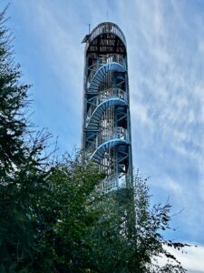 Hoher Aussichtsturm mit einer spiralförmigen Metalltreppe, von unten vor blauem Himmel gesehen.